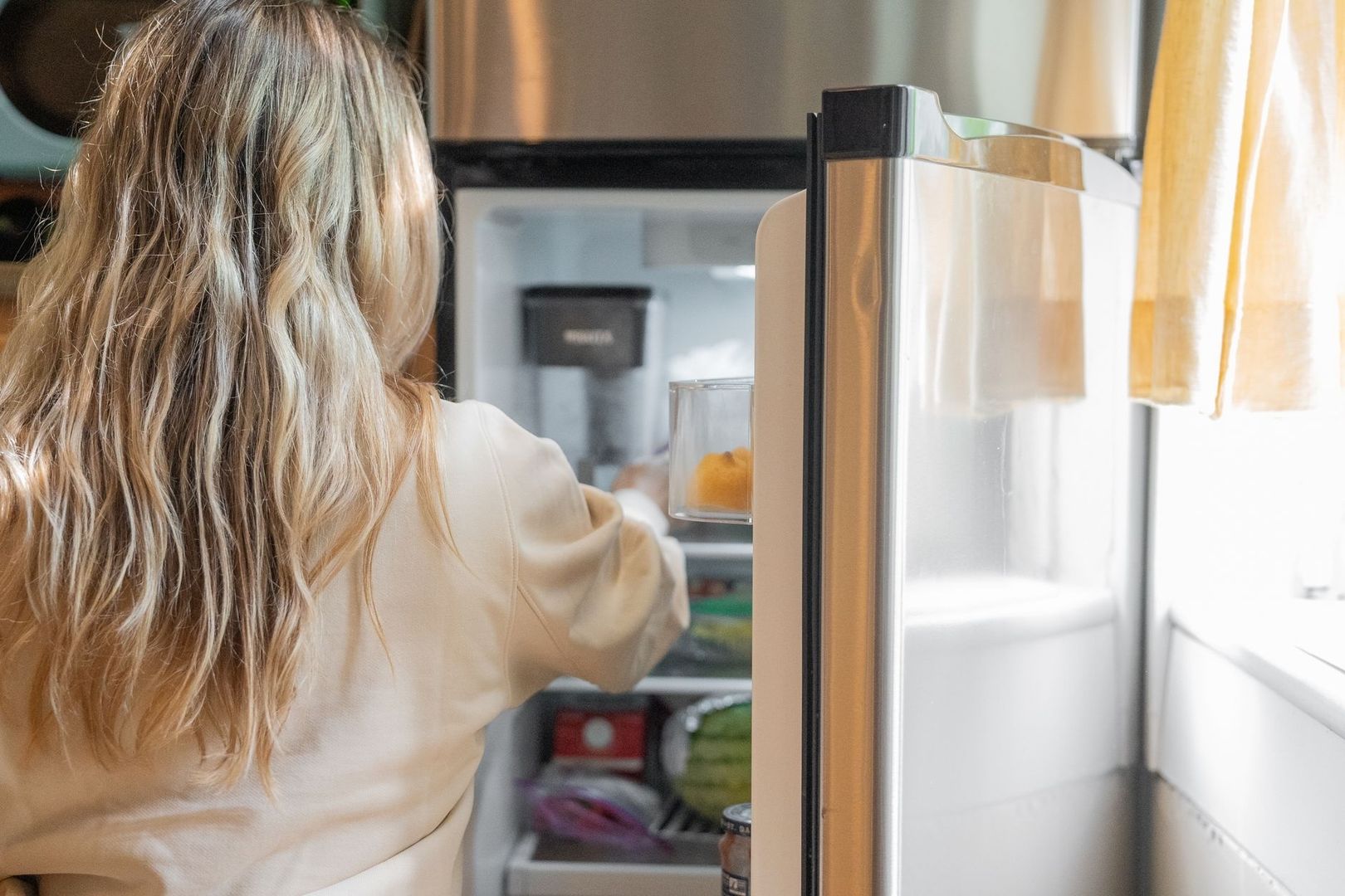 Person öffnet eine große Kühl- oder Gefriertruhe in einer Küche